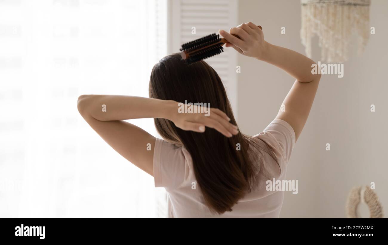 Rear view young woman combing healthy long straight hair Stock Photo