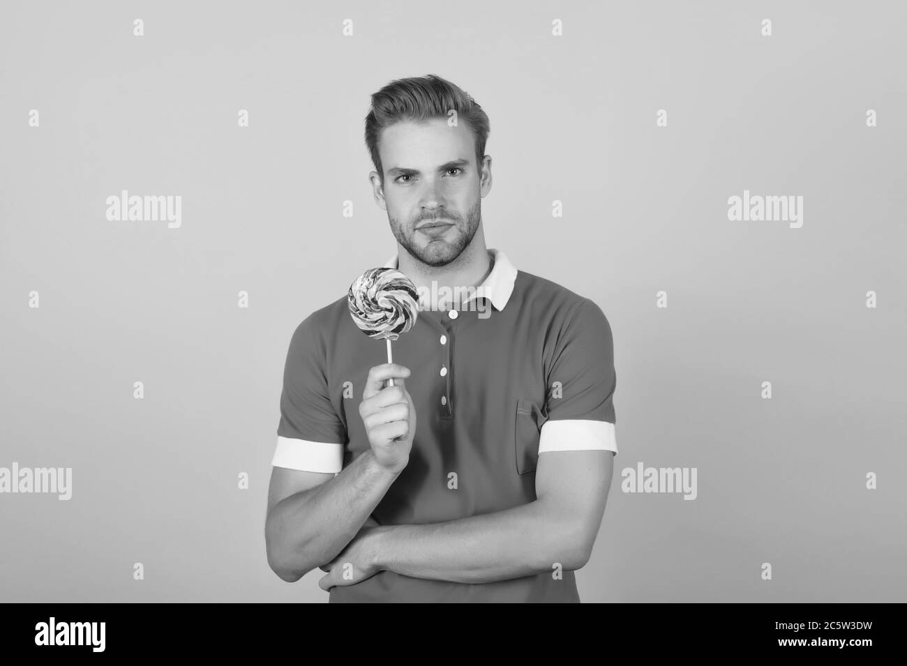 Cant wait to get a bite of lollipop. Young guy hold lollipop yellow background. Eating lollipop
