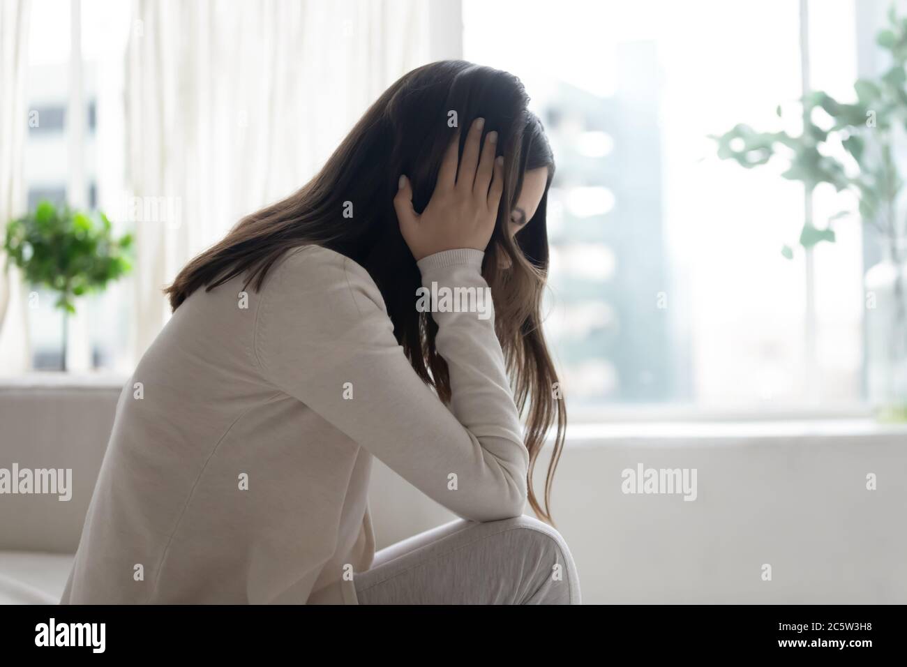 Unhappy depressed woman sitting alone, thinking about problems Stock Photo