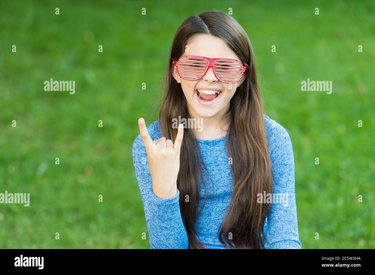 Rock is cool. Cool child show hand horns outdoors. Happy girl party on