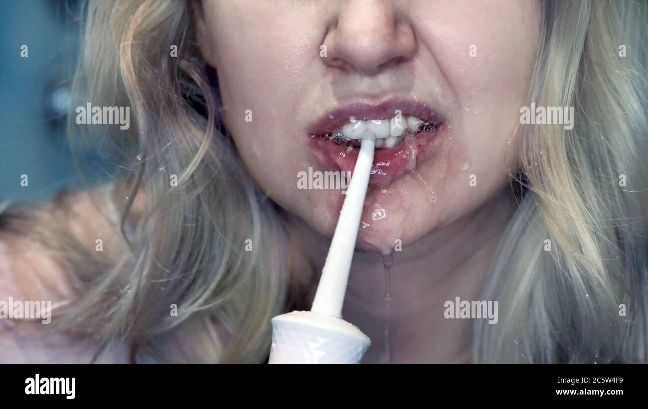 Young woman cleaning her teeth with an oral irrigator. Stock Photo