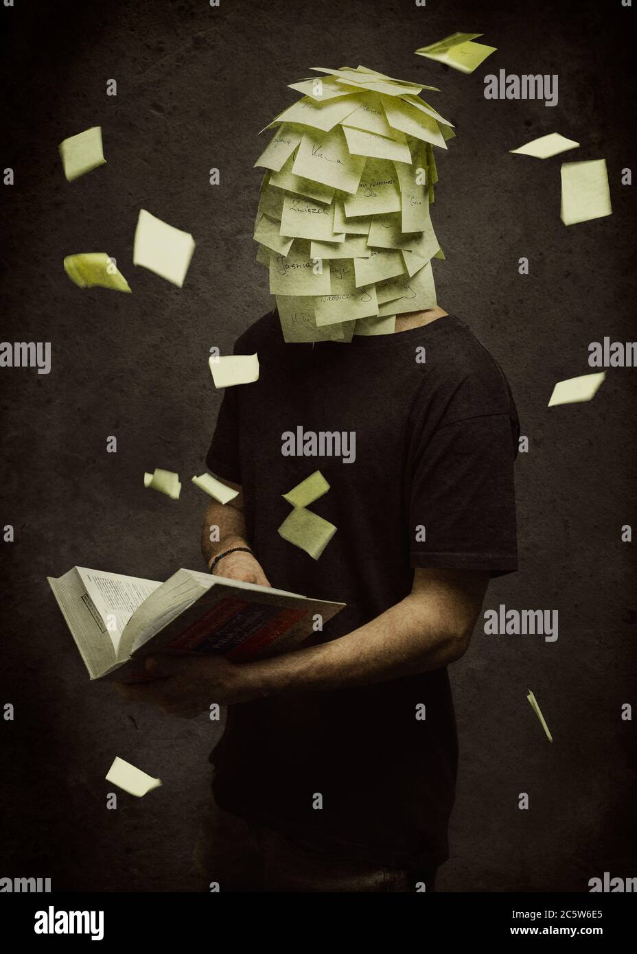 A boy looking for a translation in a dictionary whose head is completely covered with post-it notes Stock Photo