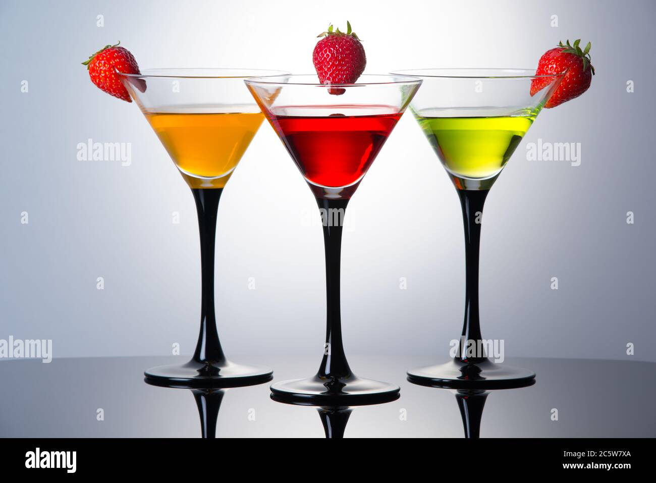 Colored drinks in martini glasses with strawberries, cocktails with liqueurs Stock Photo