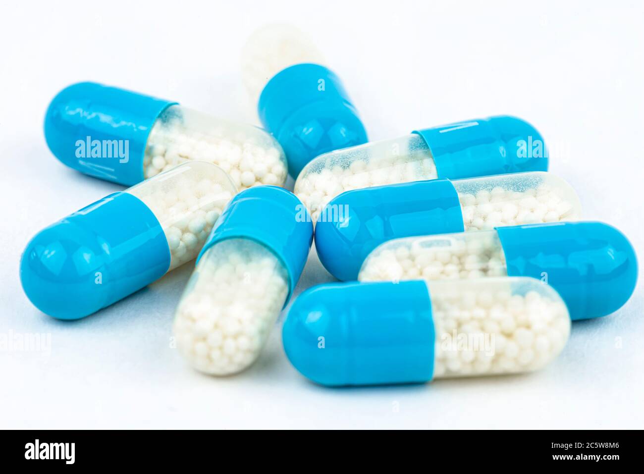 Blue gelatin capsules with white granules inside, isolated on a white