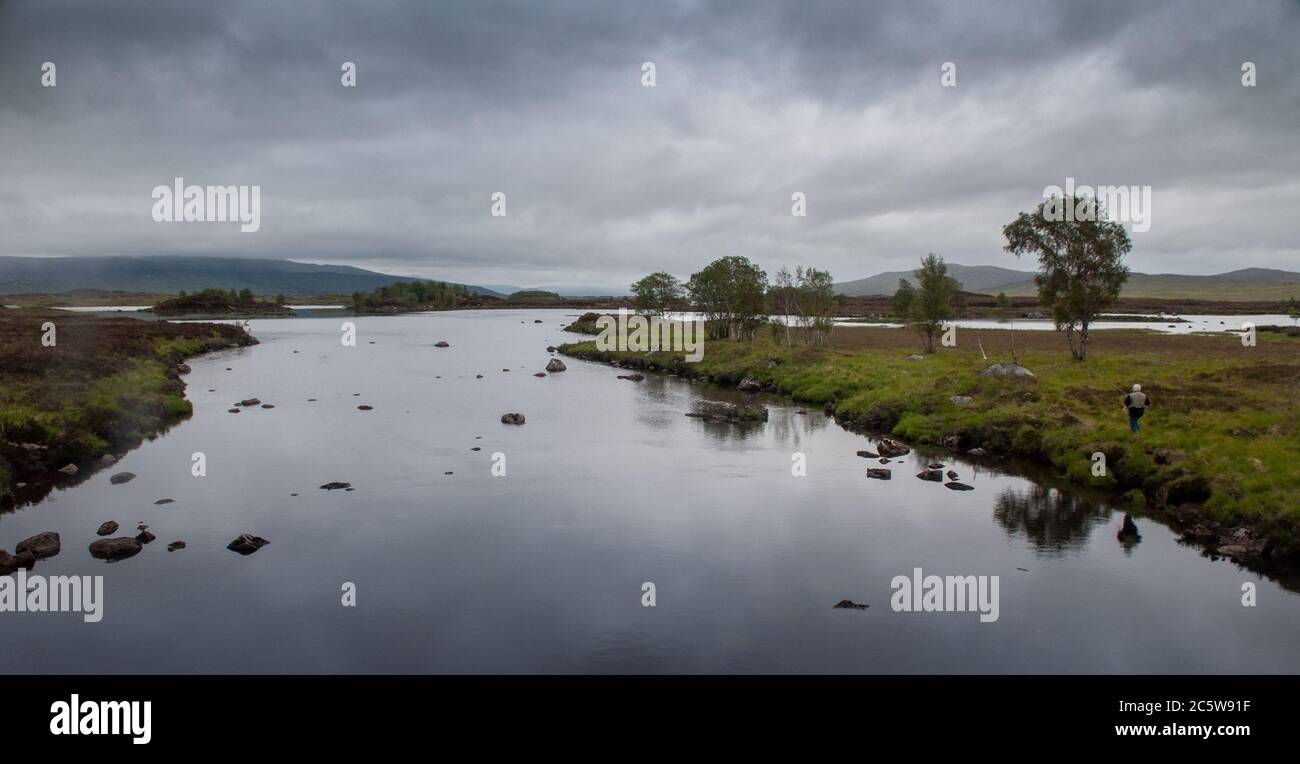 Glencoe, Scotland, UK - June 4, 2011: A fisherman stands on the banks of the River Ba on the wetland landscape of Rannoch Moor in the West Highlands o Stock Photo