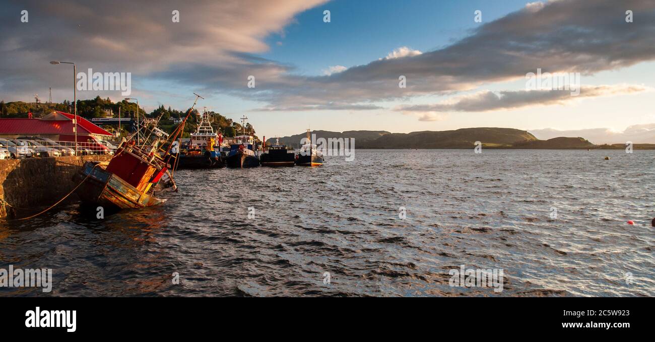 Oban, Scotland, UK - June 3, 2011: Evening sun shines on Oban Bay, the island of Kerrera and fishing boats moored on Oban quayside. Stock Photo