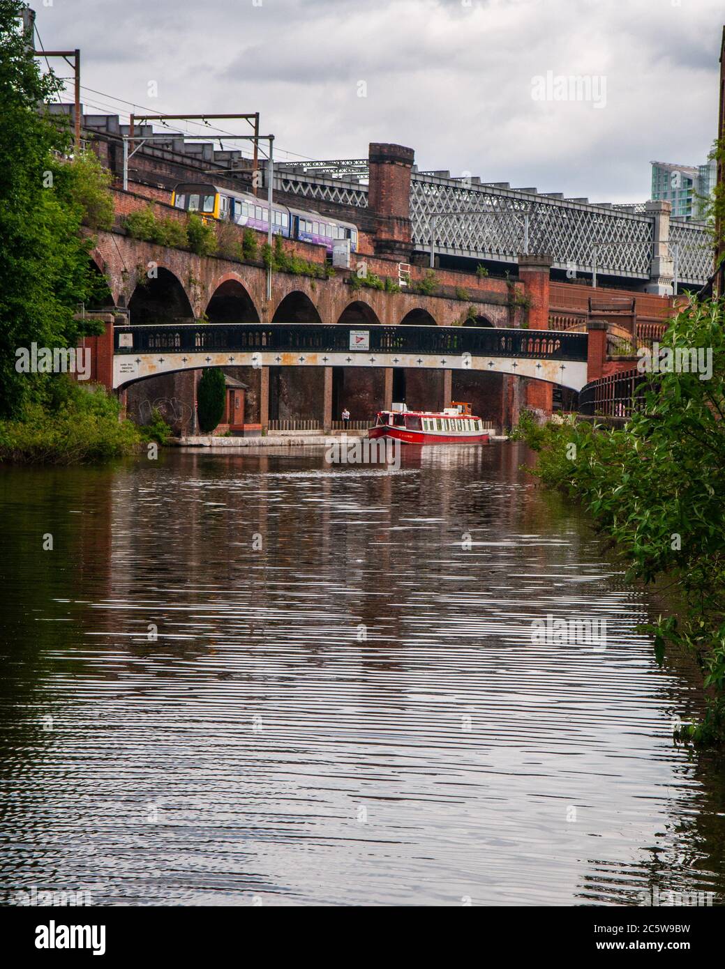 A Class 142 'Pacer' train travels along a Victorian brick viaduct above the Bridgewater Canal at Castlefield Basin in Manchester. Stock Photo