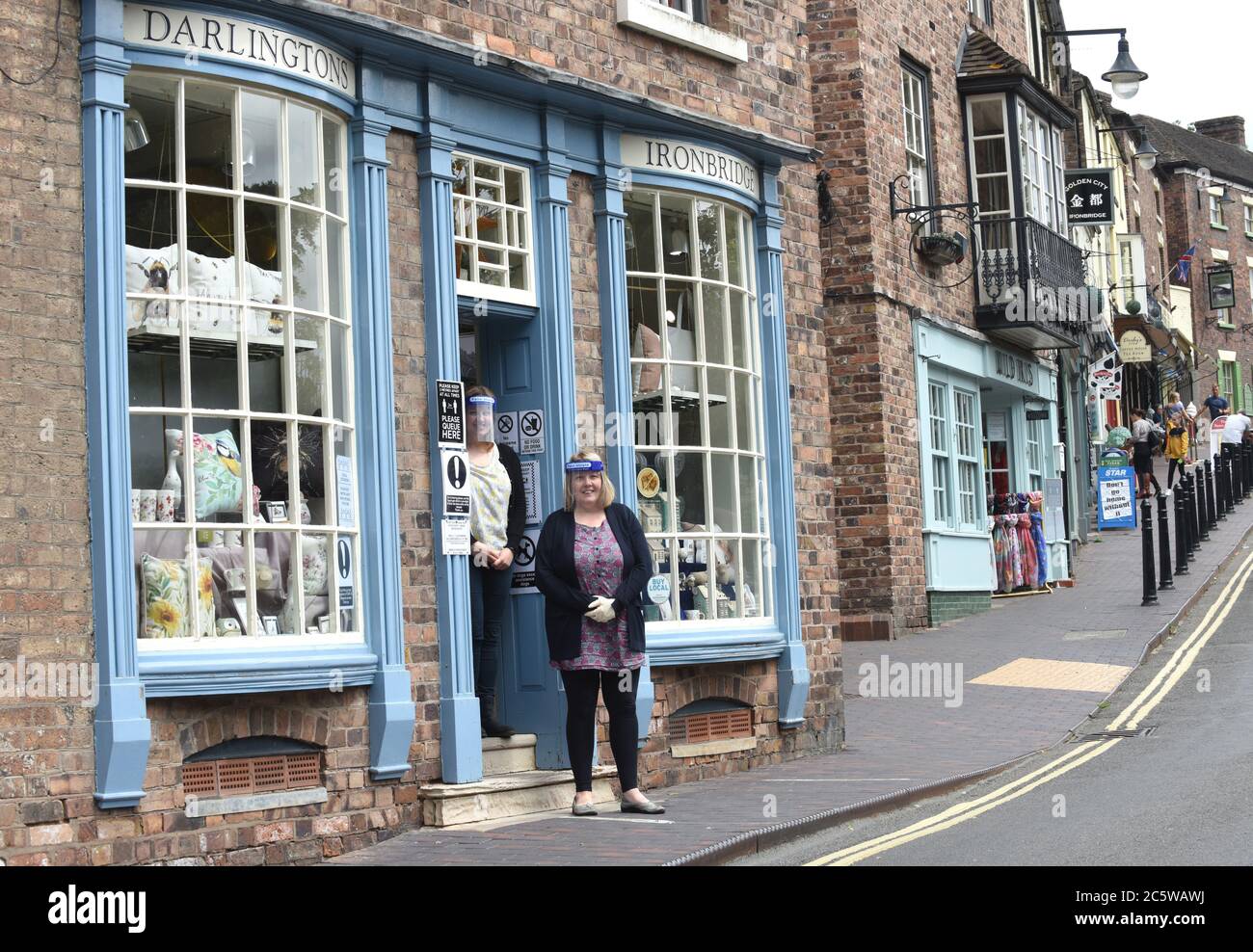 Shop owners sisters Chris and Clare Darlington wearing face visors as they welcome customers back during Covid 19 virus pandemic in Ironbridge. Stock Photo