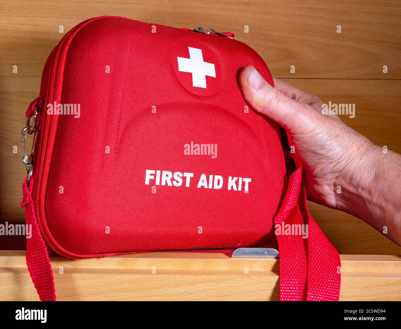 Closeup of a man’s hand reaching for a red first aid kit box in a motorhome / caravan wall