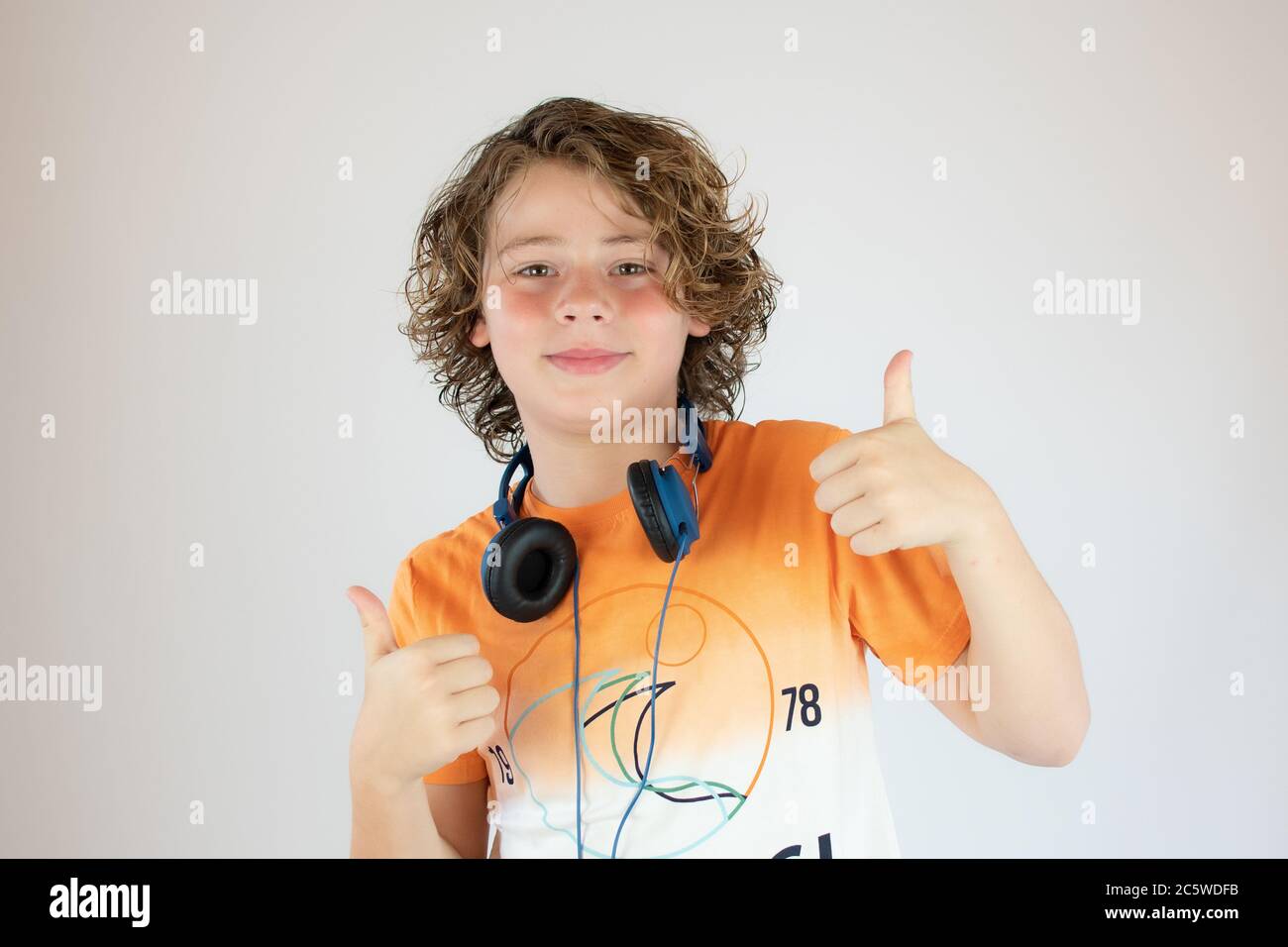 Boy in orange shirt with helmets around his neck Stock Photo - Alamy