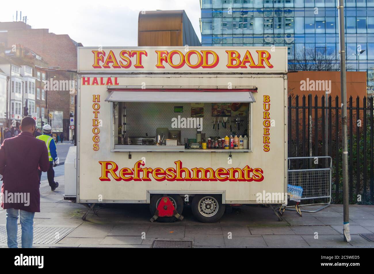 A trailer with a kitchen for selling fast foods with 'Fast food bar. Refreshments. Halal. Burgers. Hot Dogs' signs visible, in London Stock Photo