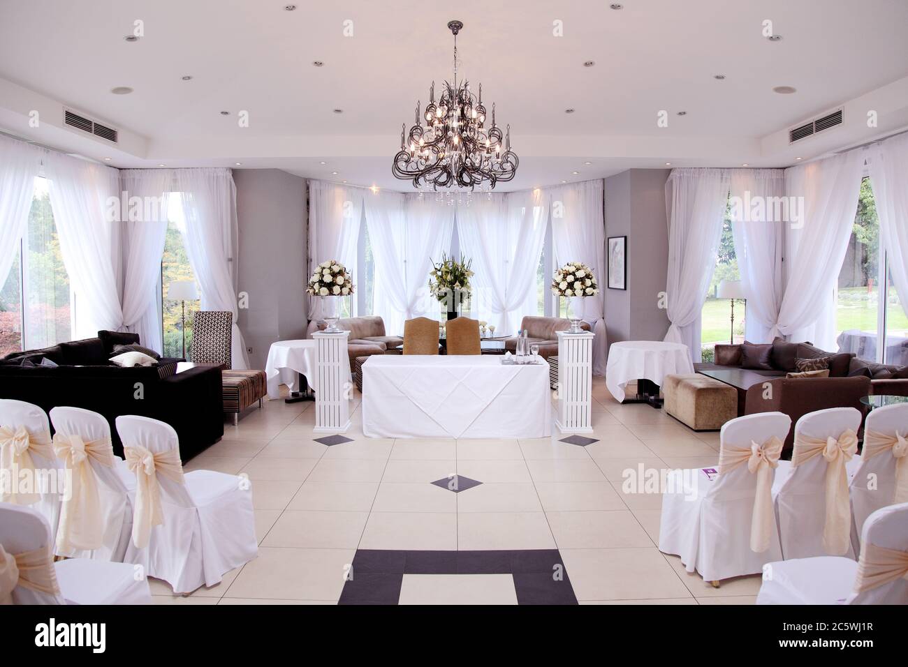 Empty closed wedding venue ceremony room or registry office featuring striking modern chandeliers. Stock Photo