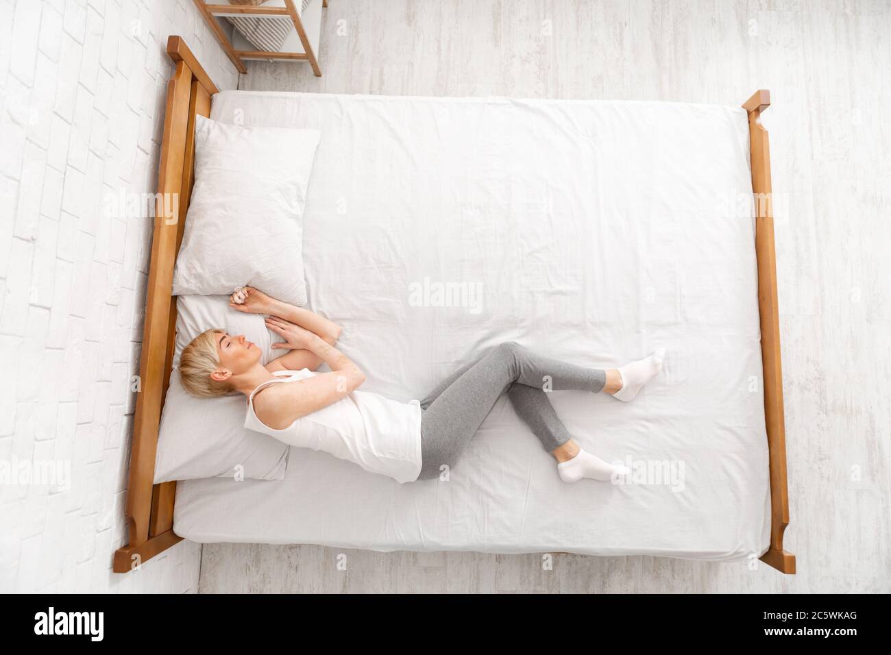 Middle aged lady with vitiligo sleeping in bed, top view Stock Photo