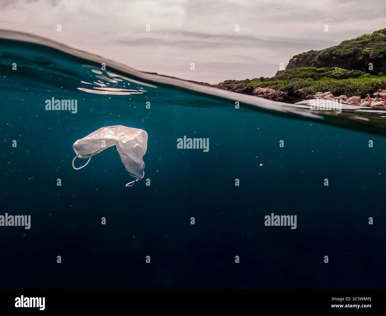 Protective mask discarded and thrown on the ocean. Abandoned facemask