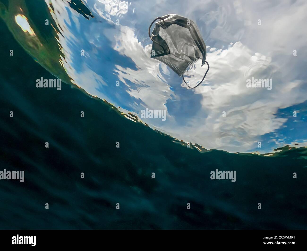 Protective mask discarded and thrown on the ocean. Abandoned facemask