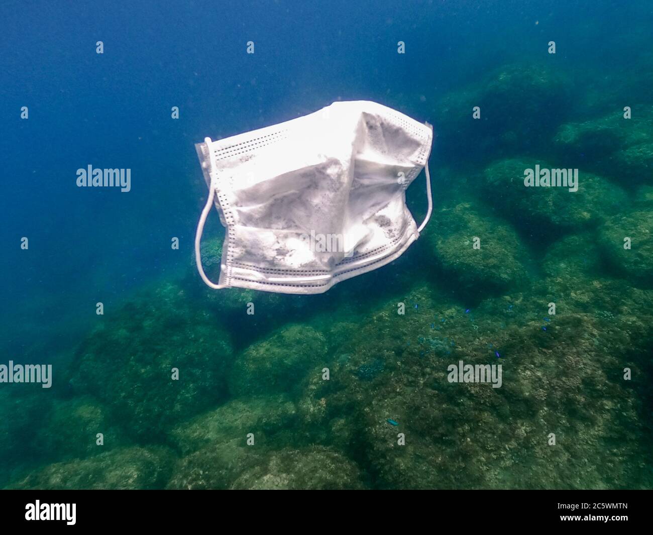 People throws out a medical face mask on the ocean water. Used surgical