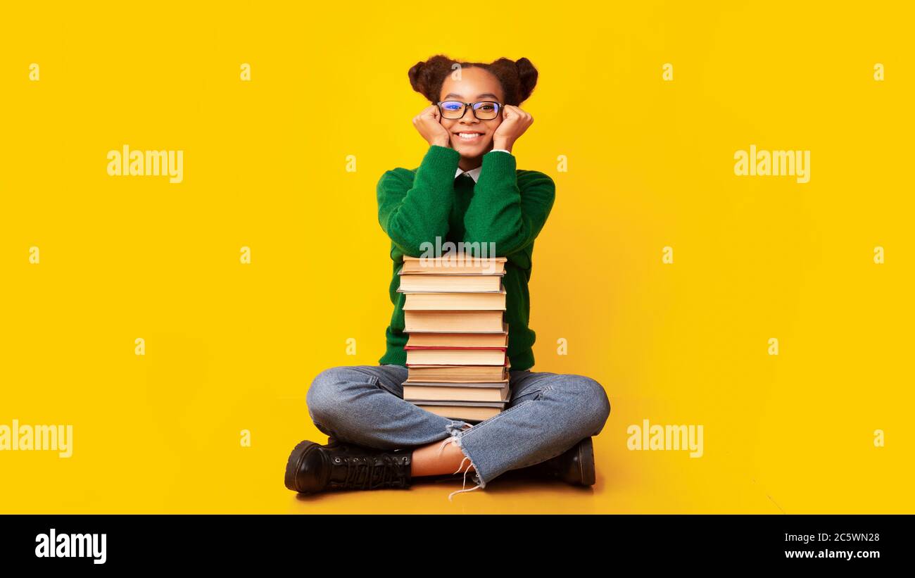 Afro schoolgirl with pile of books at studio Stock Photo - Alamy
