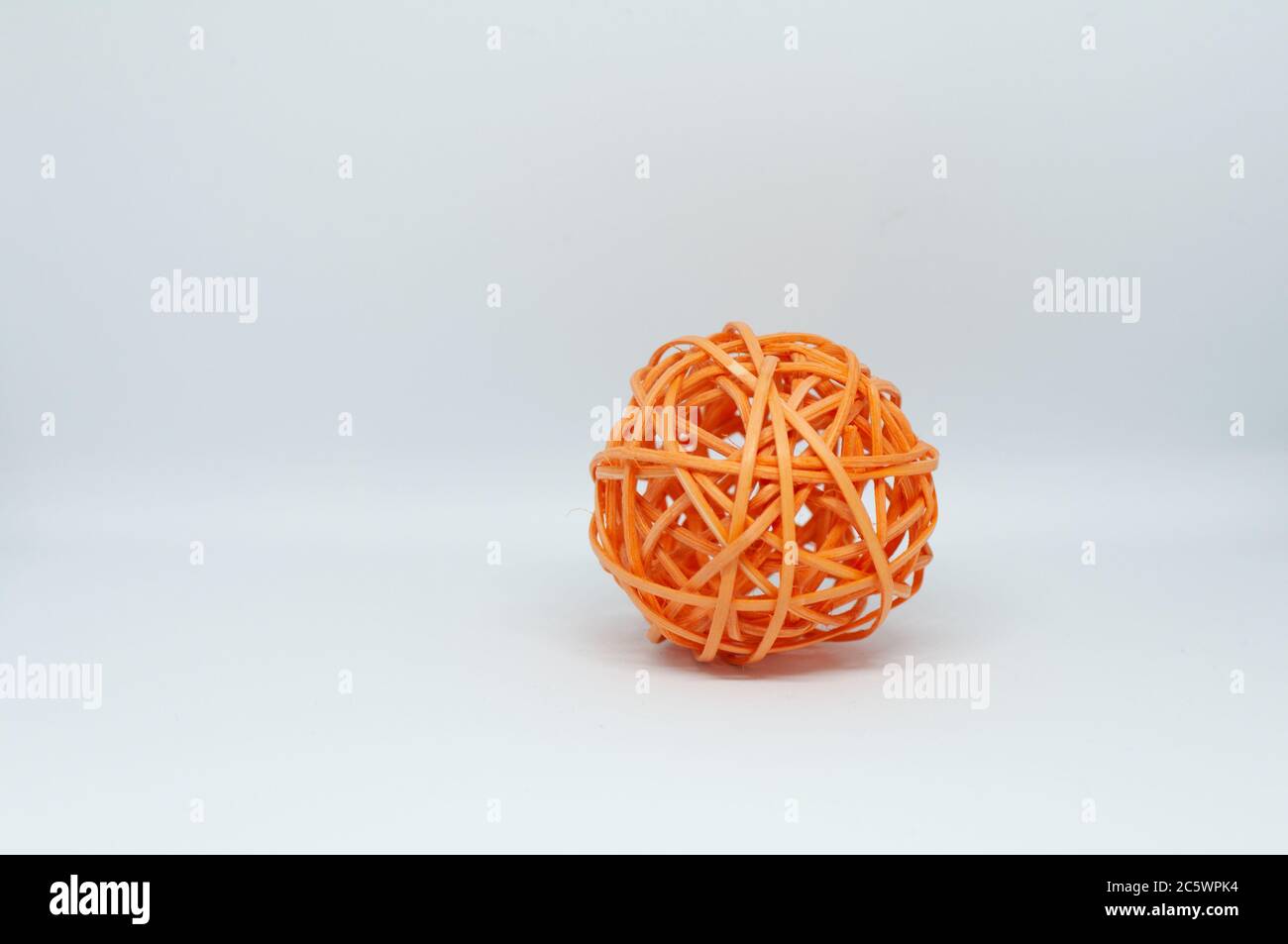 Dry reeds designed into an orange ball for decoration on white ...