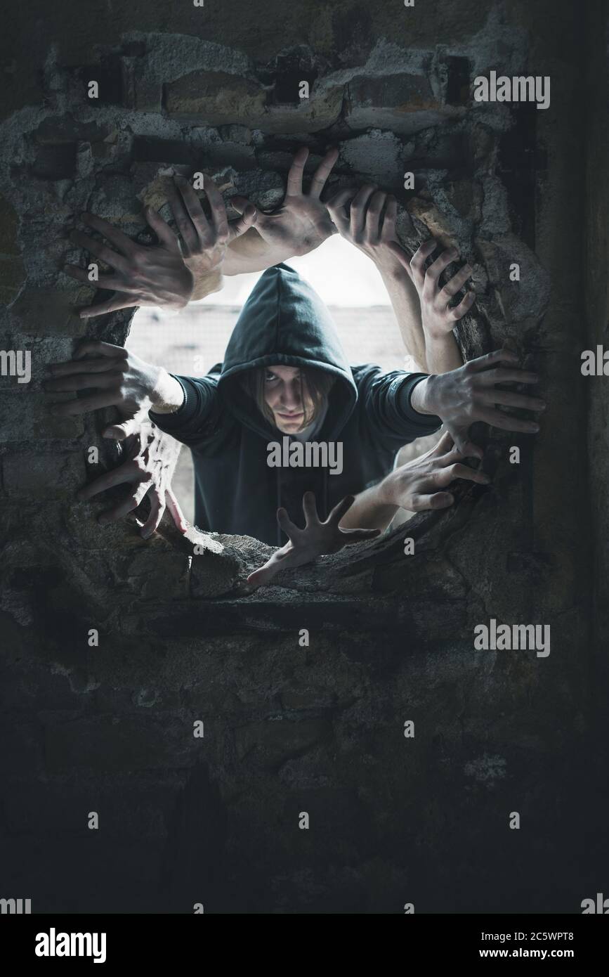 Young man with hood reaching out of hole with many hands concept Stock Photo