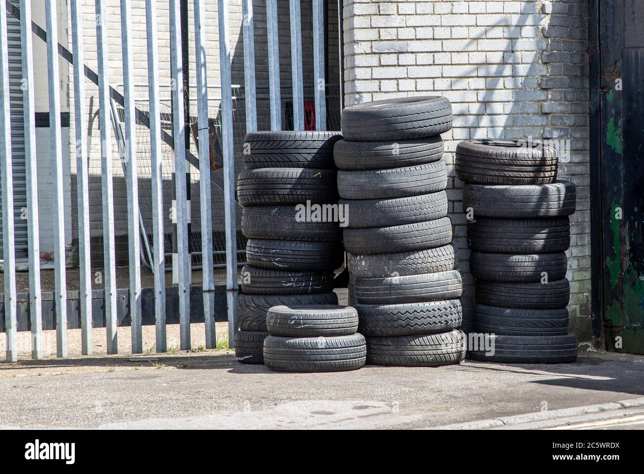 Used car tyres or tires stacked on top of each other outside a car garage or workshop Stock Photo