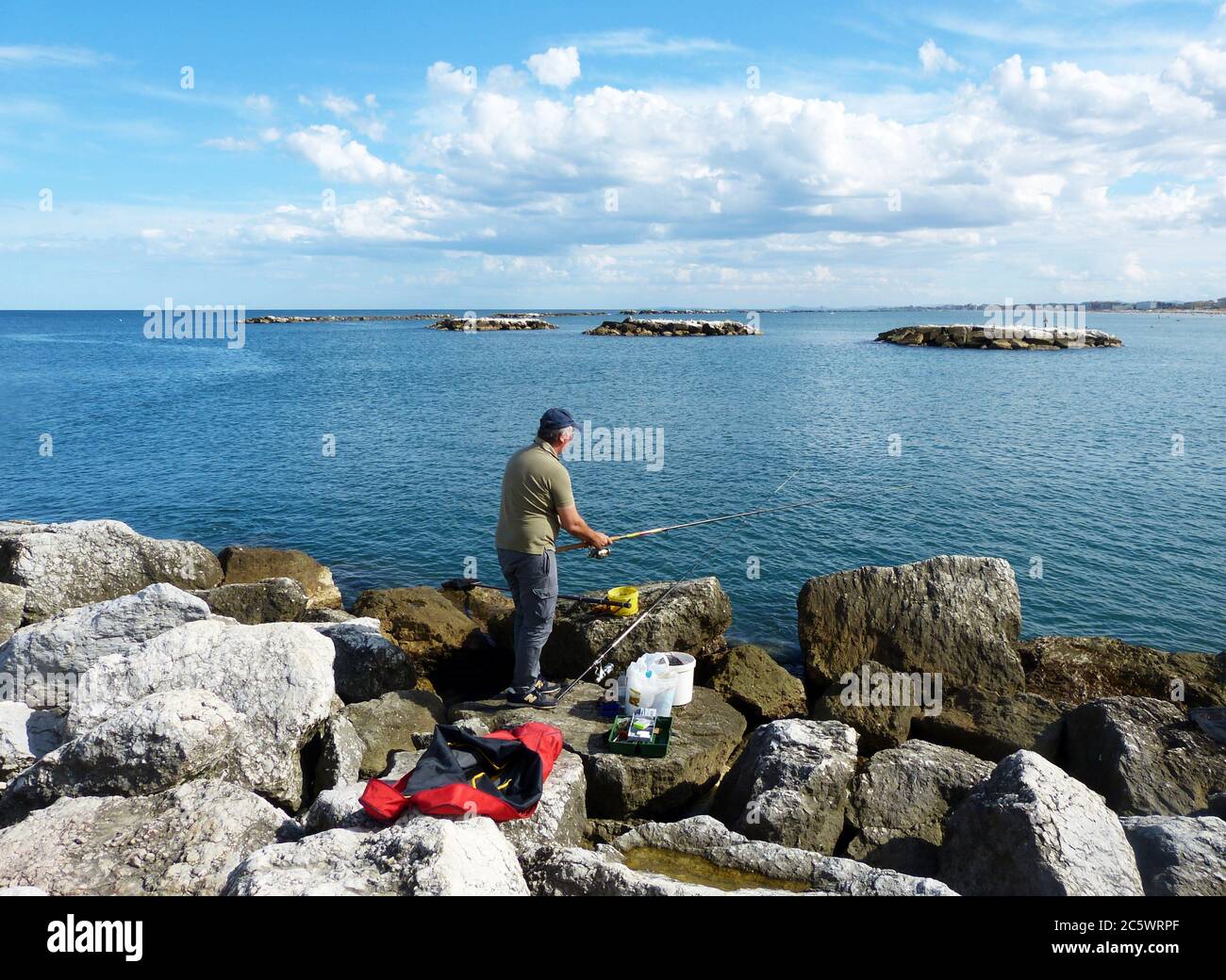 Fisherman on the rocks of Cesenatico. Adriatic sea. Italy Stock Photo