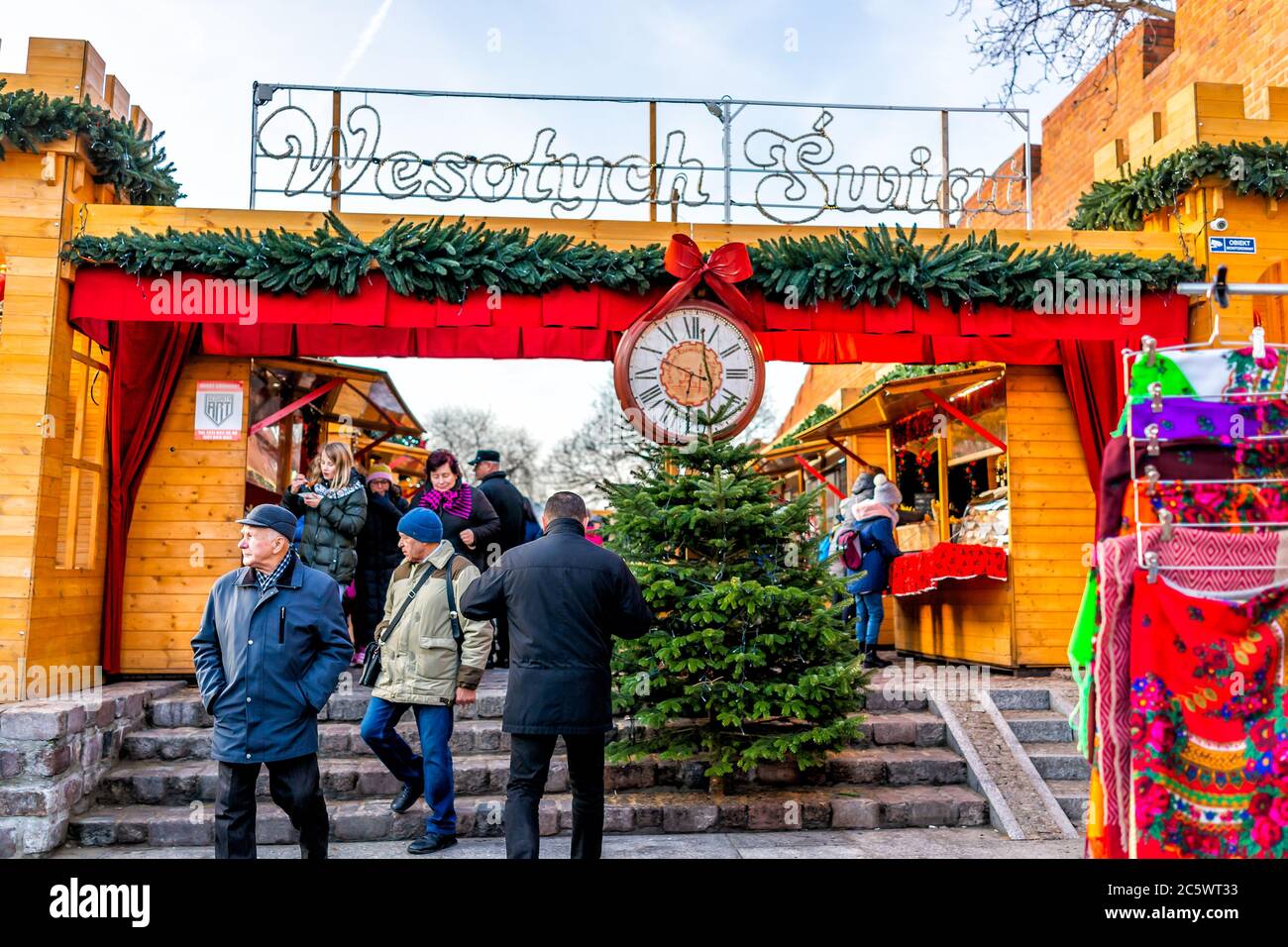 Warsaw, Poland - December 19, 2019: Old town Warszawa during day with Christmas market near royal castle square people walking by entrance with clock Stock Photo