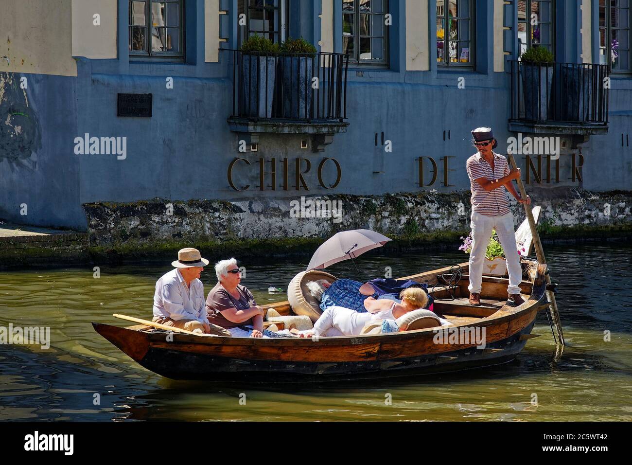 small boat, four tourists relaxing, boatman steering with paddle, job, old wood boat, vacation, canal, water, Flanders, Europe, Ghent; Belgium, summer Stock Photo