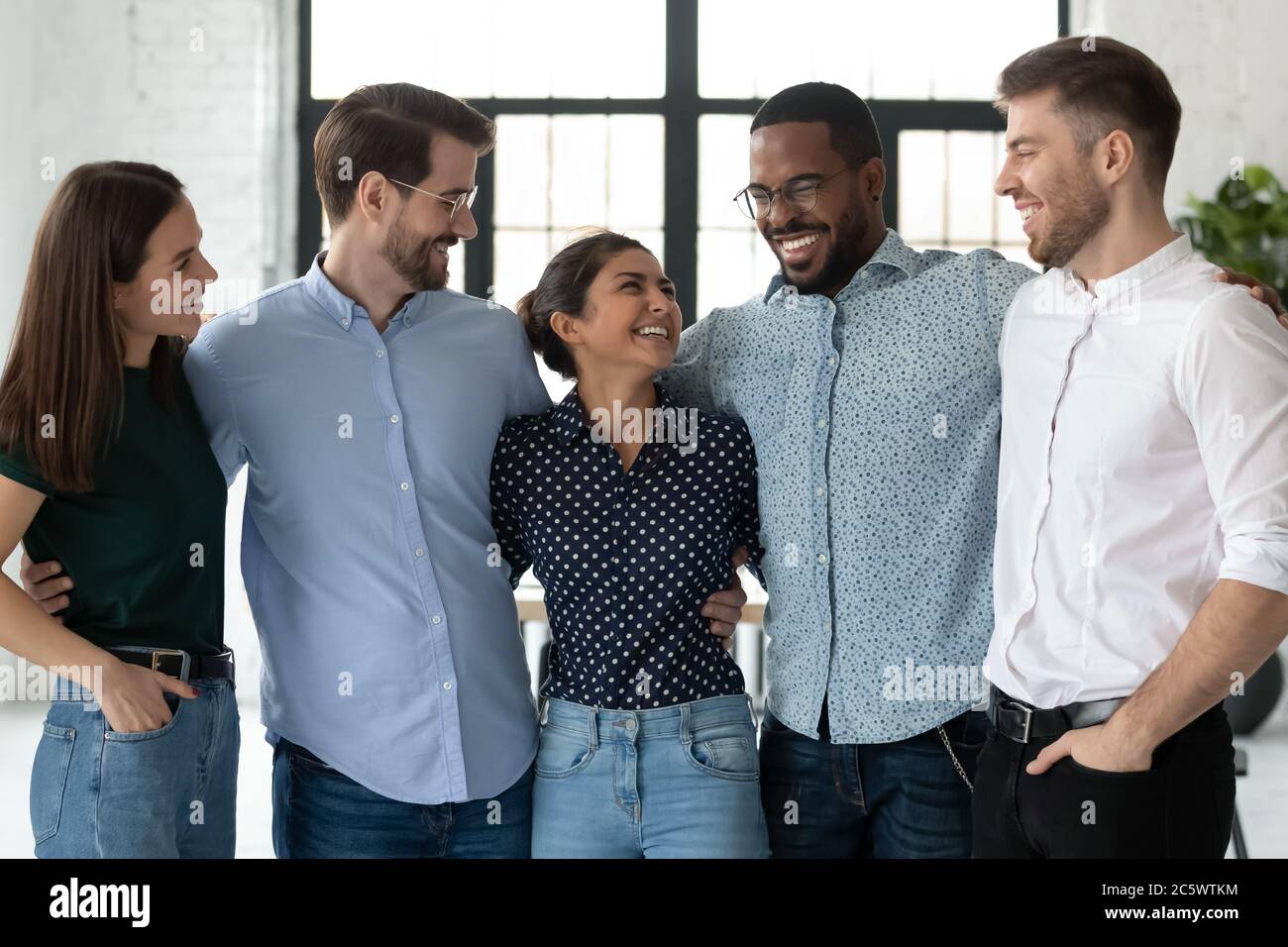 Excited diverse colleagues hugging joking enjoy meeting and friendship Stock Photo