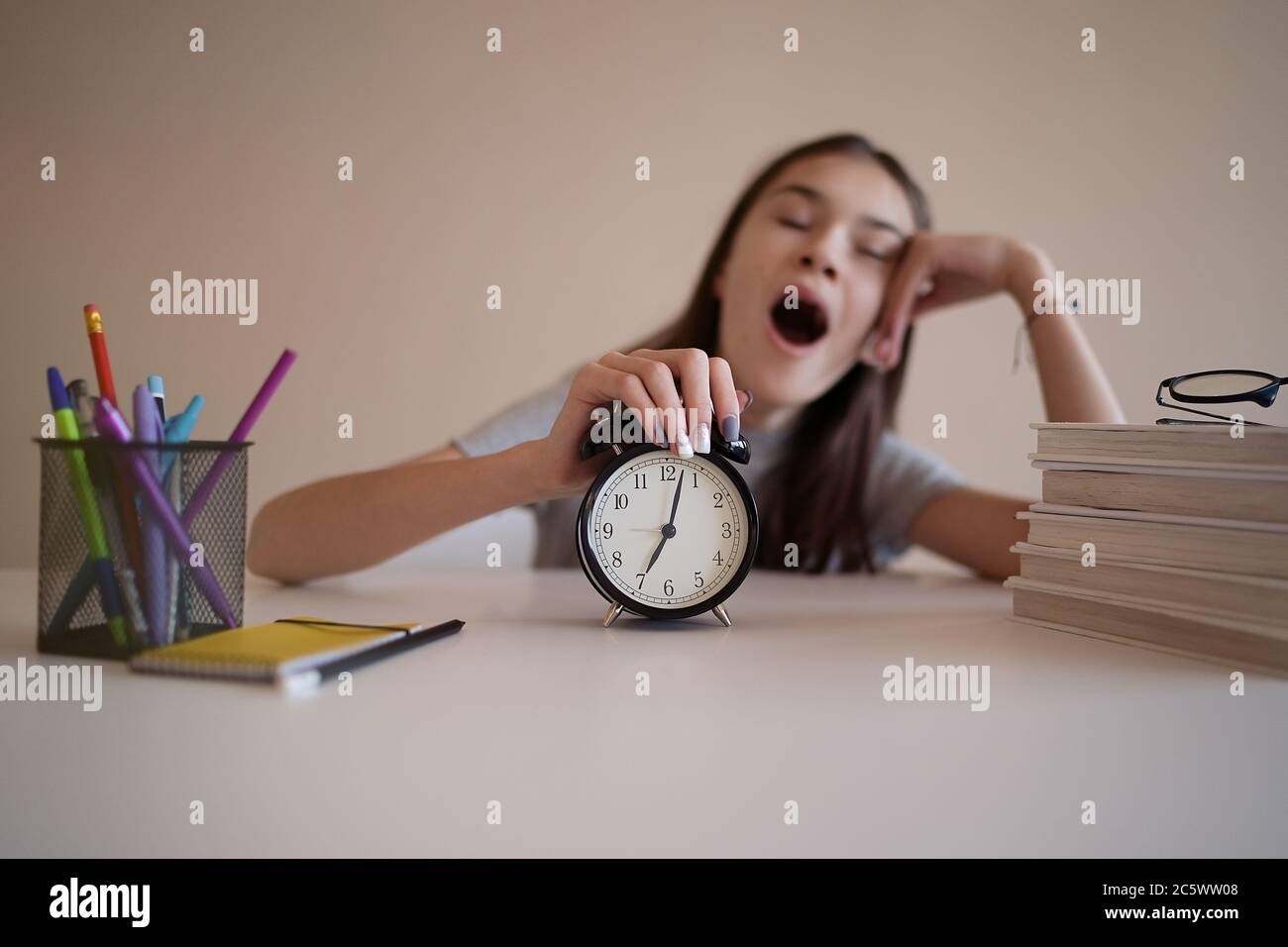 Teenage girl is yawning from studying and doing her homework. Tired and desperate student. Education, children and school concept Stock Photo