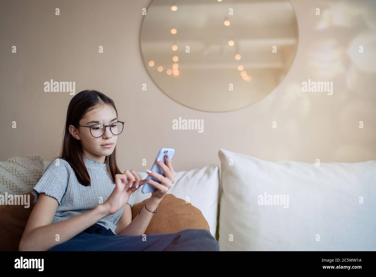 Cute teenage girl sitting on sofa at home and using mobile phone Stock ...