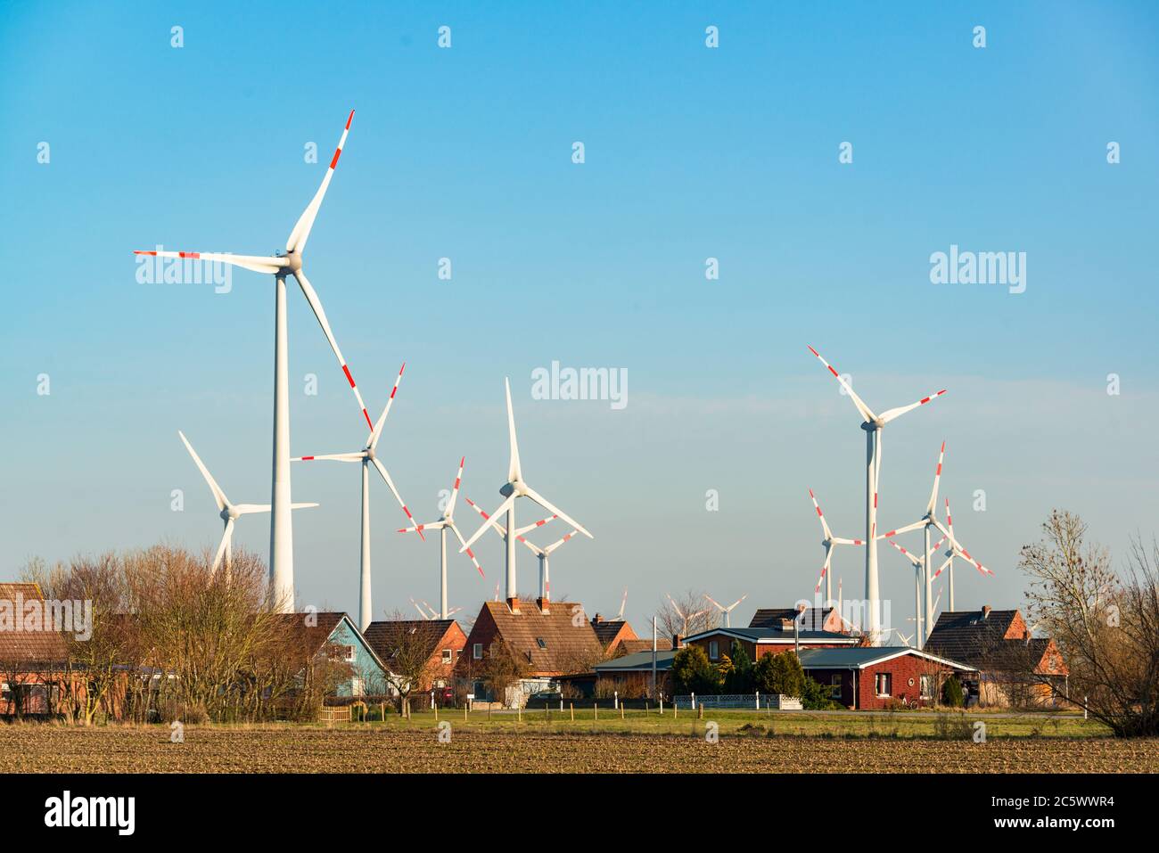 Ein großer Windpark direkt neben einer kleinen Ortschaft an der Nordseeküste in Dithmarschen Stock Photo