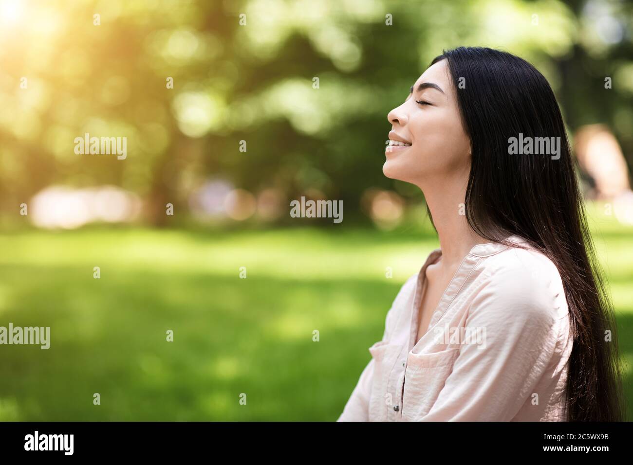 Portrait of relaxed asian girl breathing deeply with closed eyes in park Stock Photo