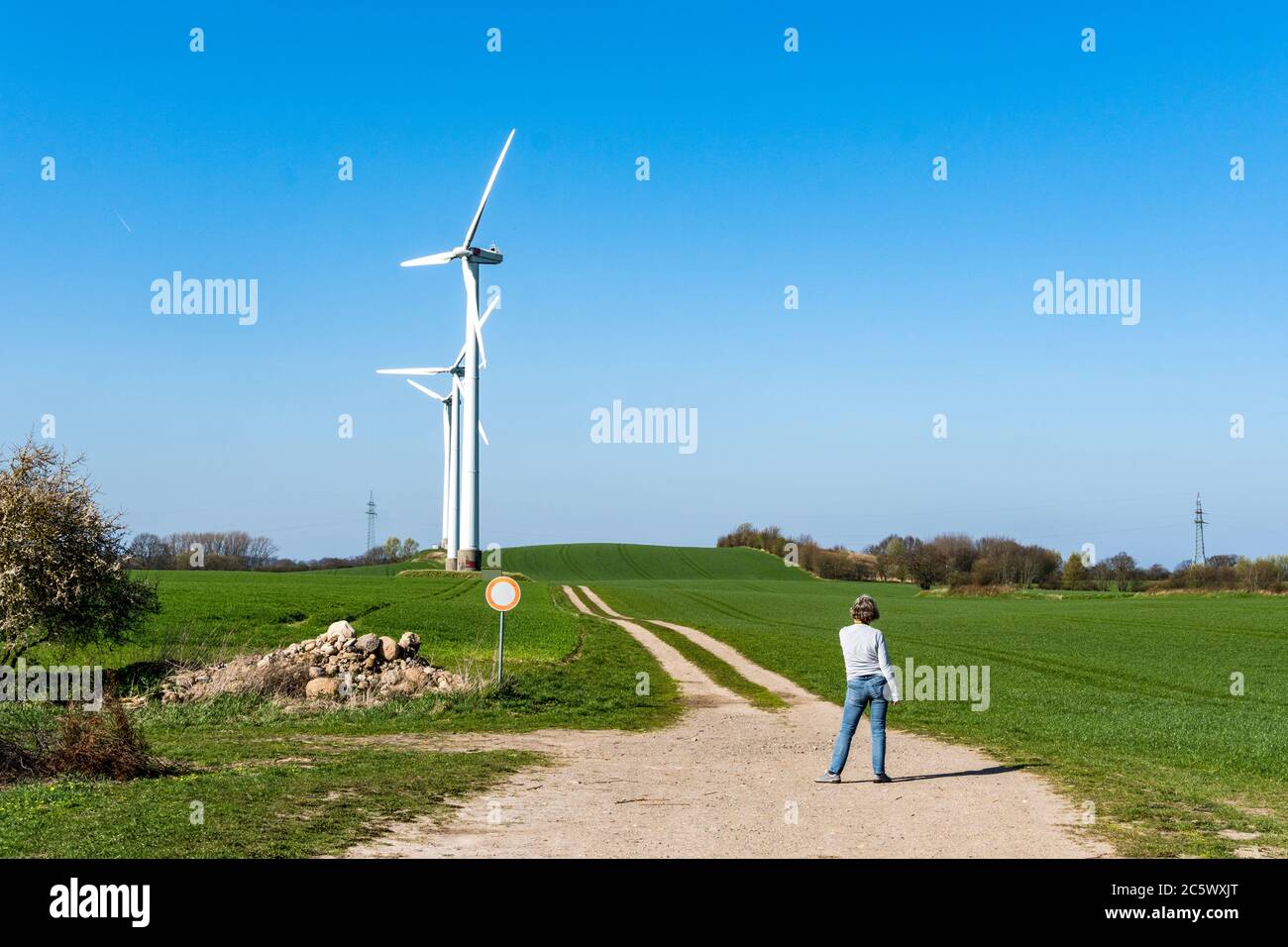Frau am Wanderweg vor einer Windkraftanlage Stock Photo