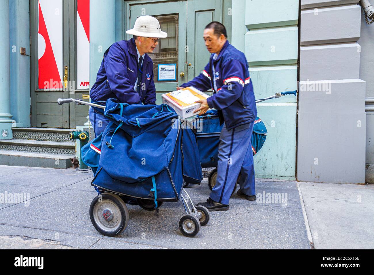 New York City,NYC NY Lower,Manhattan,SoHo,Broome Street,Asian man men male adult adults,mailman,letter carrier,postie,USPS,postal service,package,unif Stock Photo