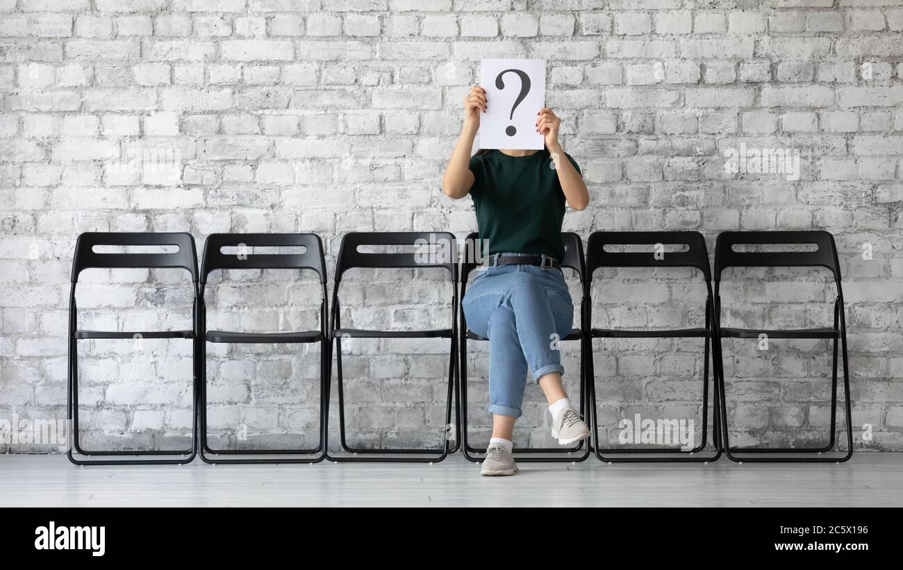 Anonymous woman hiding her face behind paper with question mark Stock Photo
