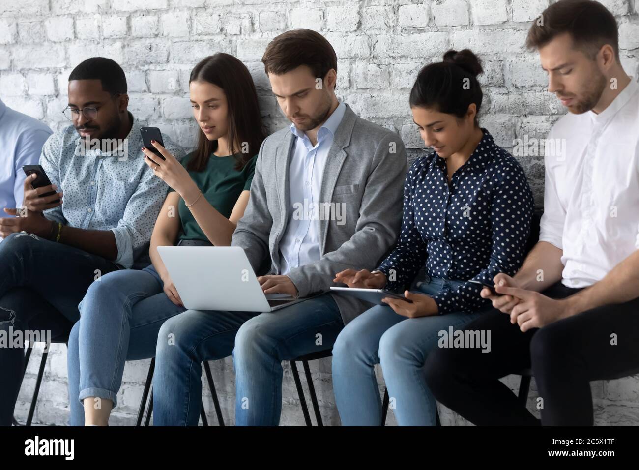 Multiracial applicants focused in gadgets while await for job interview Stock Photo
