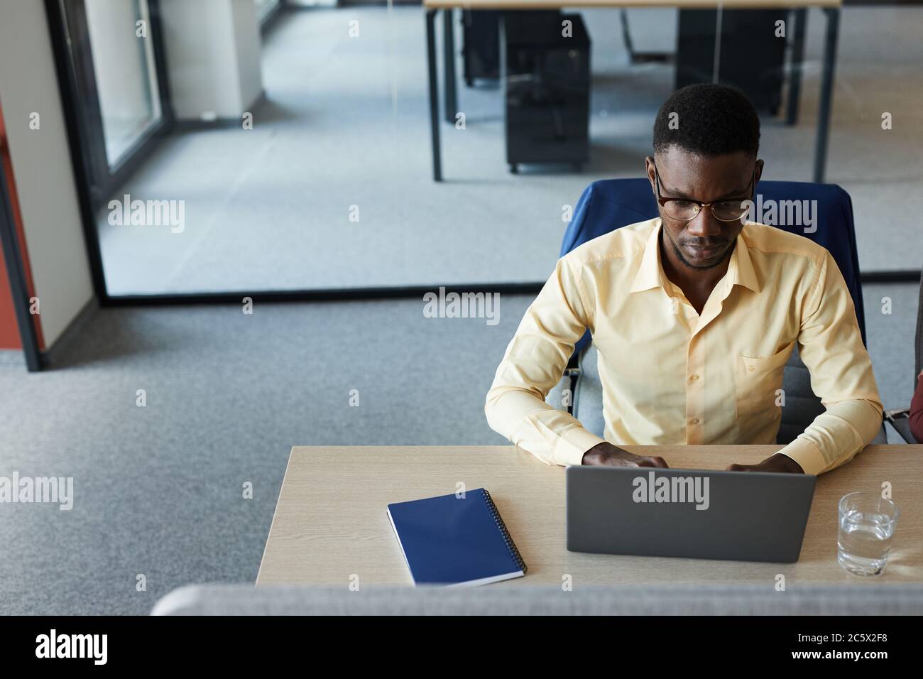 Minimal high angle portrait of elegant African-American businessman using laptop while working at desk in modern office, copy space Stock Photo