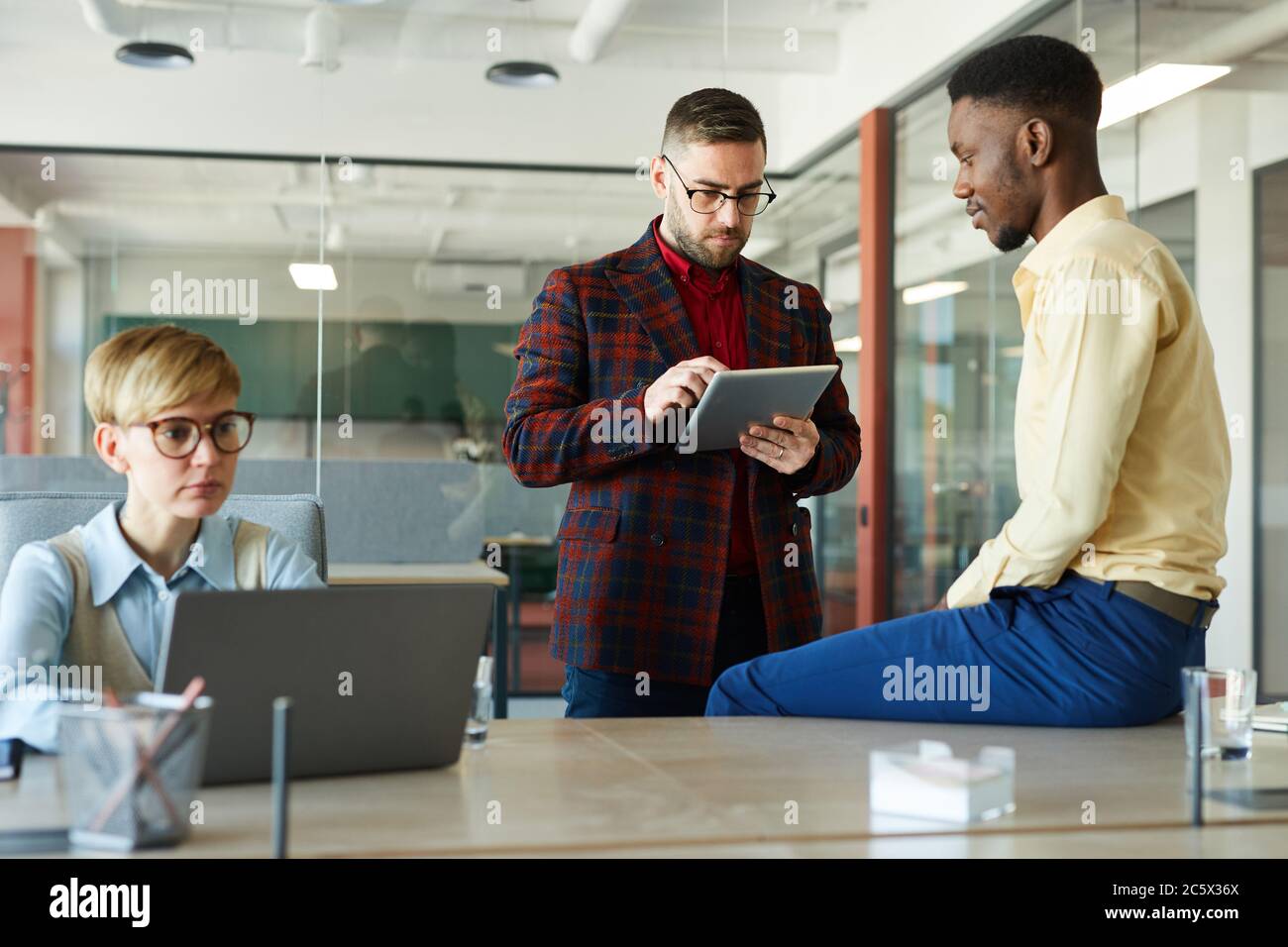 Portrait of modern multi-ethnic business team collaborating on work project in conference room, focus on bearded businessman using digital tablet Stock Photo
