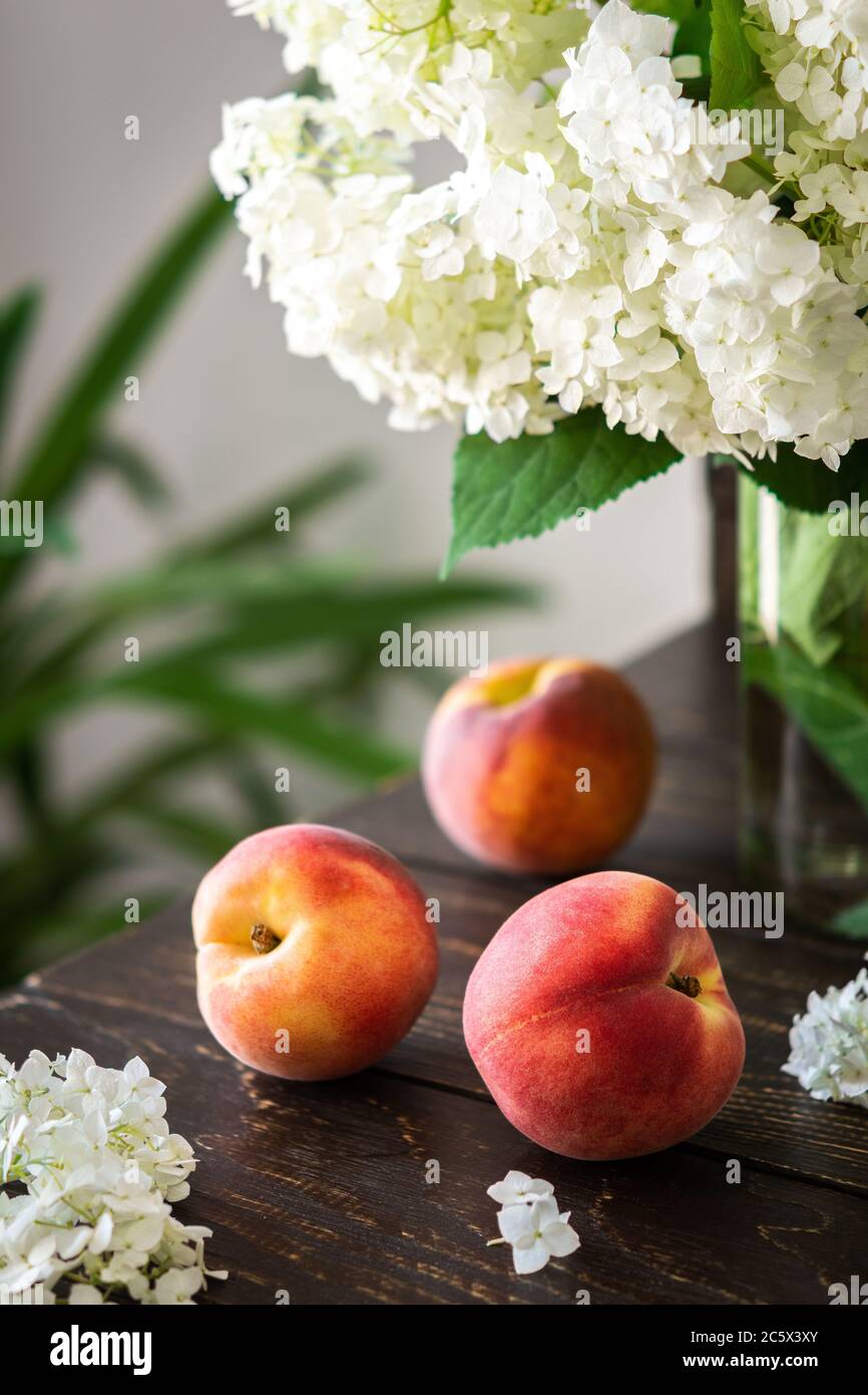 Vase of flowers viburnum opulus Roseum and ripe juicy peaches Stock Photo