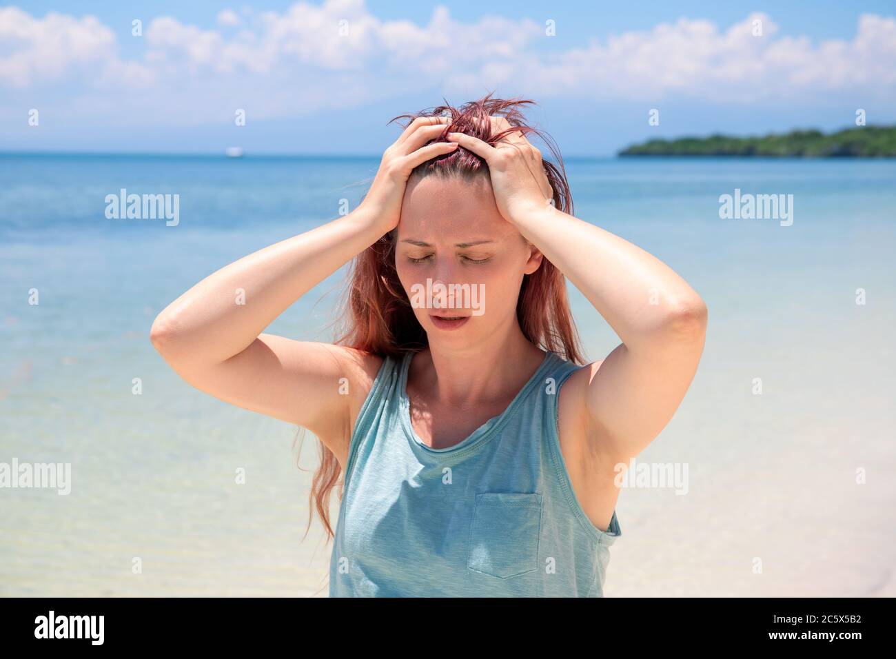 Woman with severe headache on vacation. Bright sun negative impact