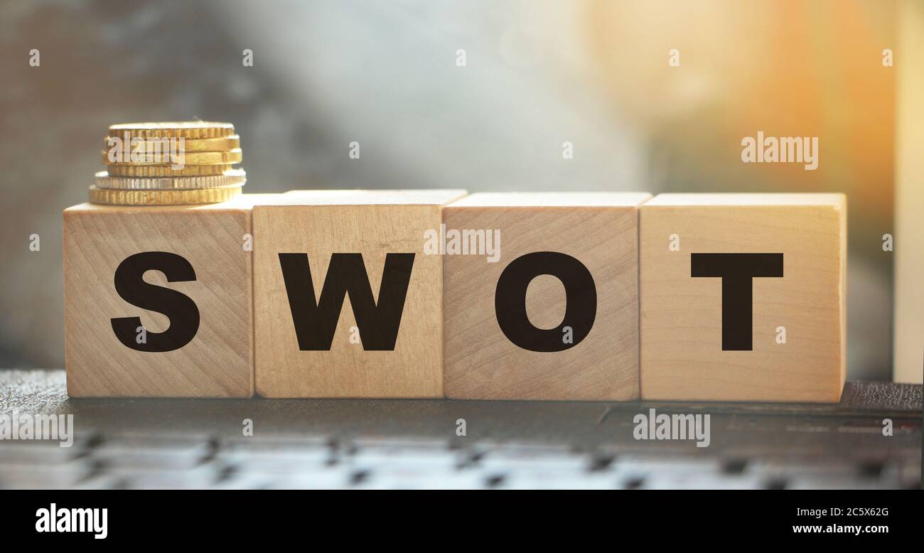 SWOT on wooden cubes and coins on computer keyboard. Business concept Stock Photo
