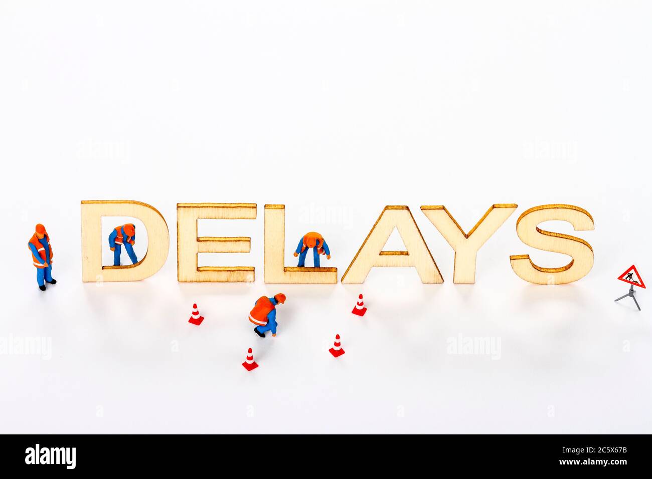 Wooden delays sign with miniature figure workmen and traffic cones Stock Photo