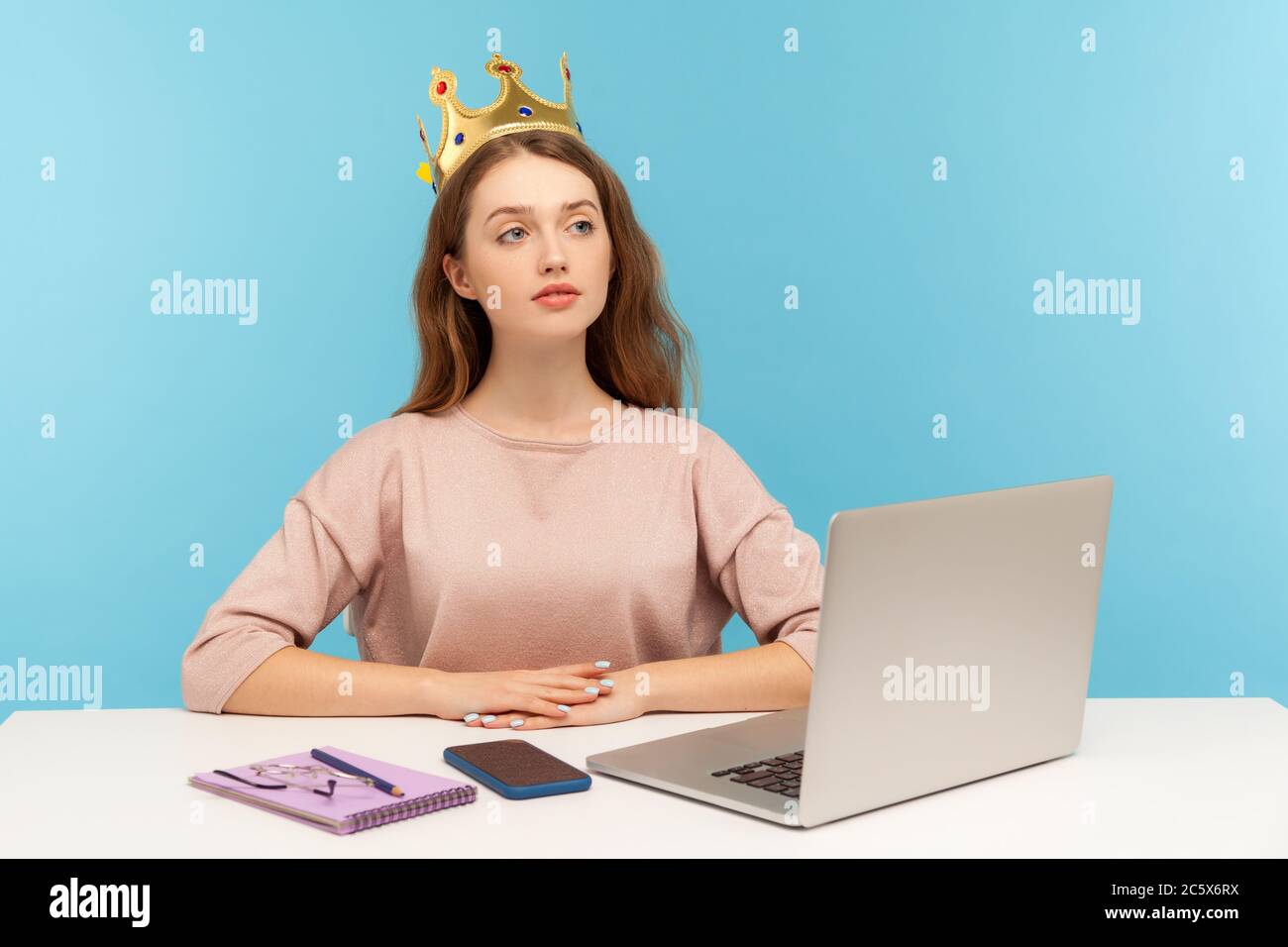 I am big boss. Proud self-confident authoritative businesswoman wearing crown on head, sitting in her office workplace and looking with arrogance. ind Stock Photo