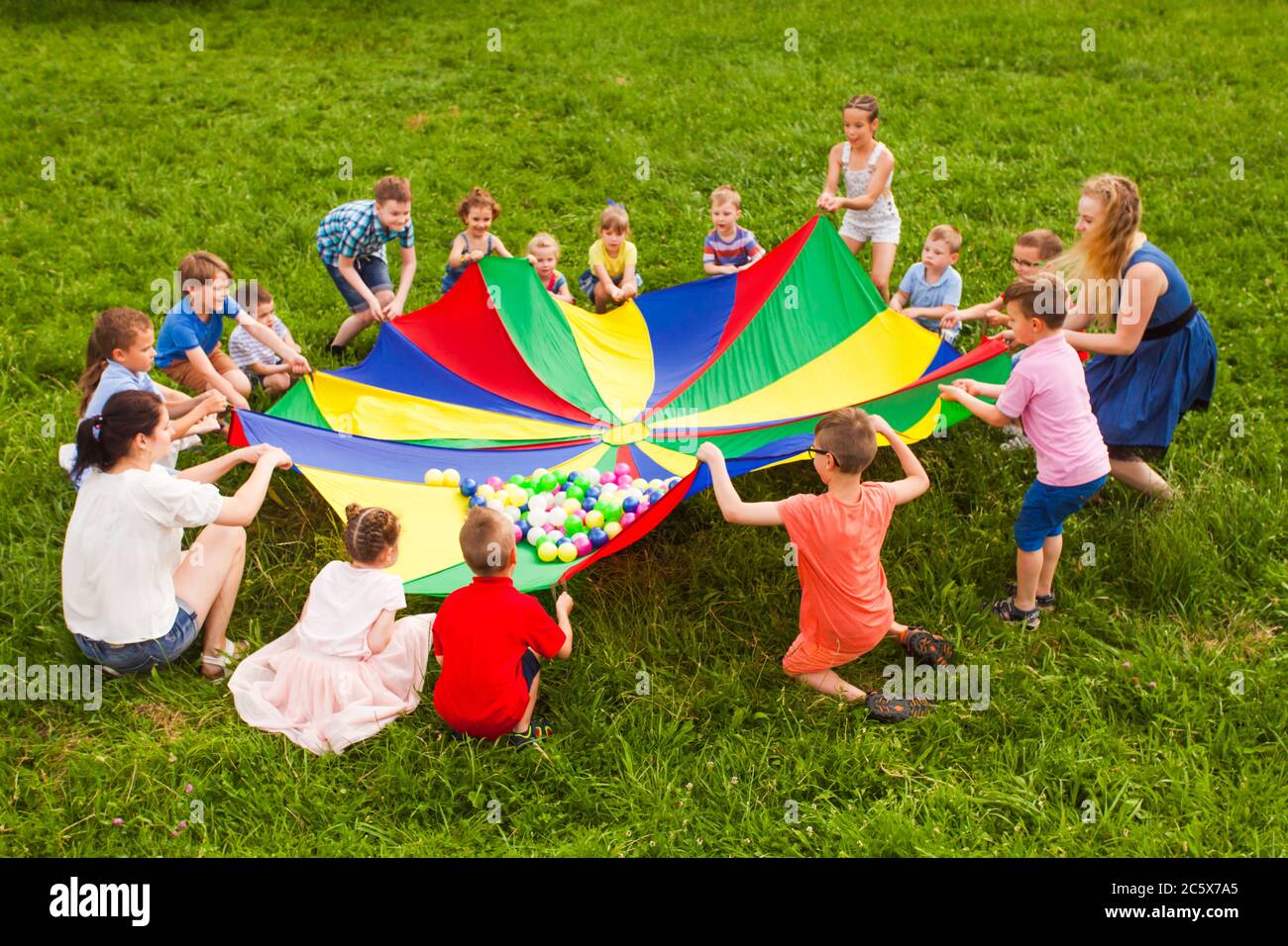 Cheerful kids playing with multicolor parachute and small balls Stock Photo Alamy