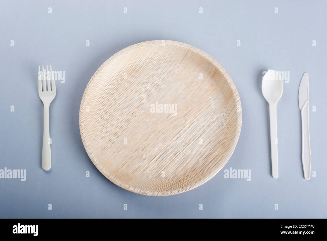 Disposable plate, fork, spoon and knife on light grey background Stock Photo