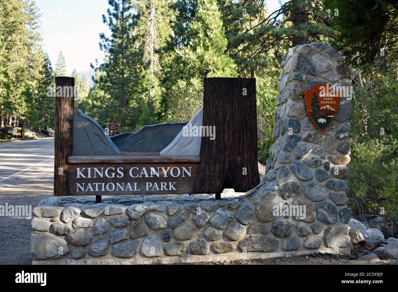 Entrance sign for Kings Canyon National Park.  The sign is brown with grey sculpting to simulate a canyon on stone foundation.  NPS Sign.  California. Stock Photo