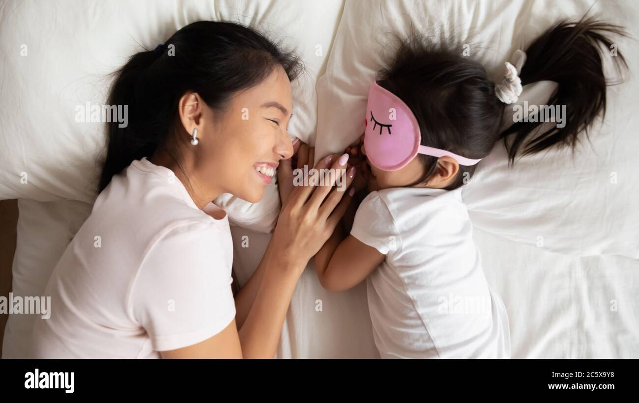 Smiling caring asian ethnic mommy watching little baby sleeping. Stock Photo