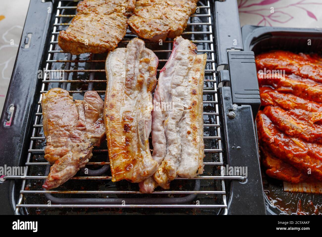 Top view of piece of barbecue pork belly and grilled steak on Electric Grill  Griddle surrounded with raw meat on side Stock Photo - Alamy