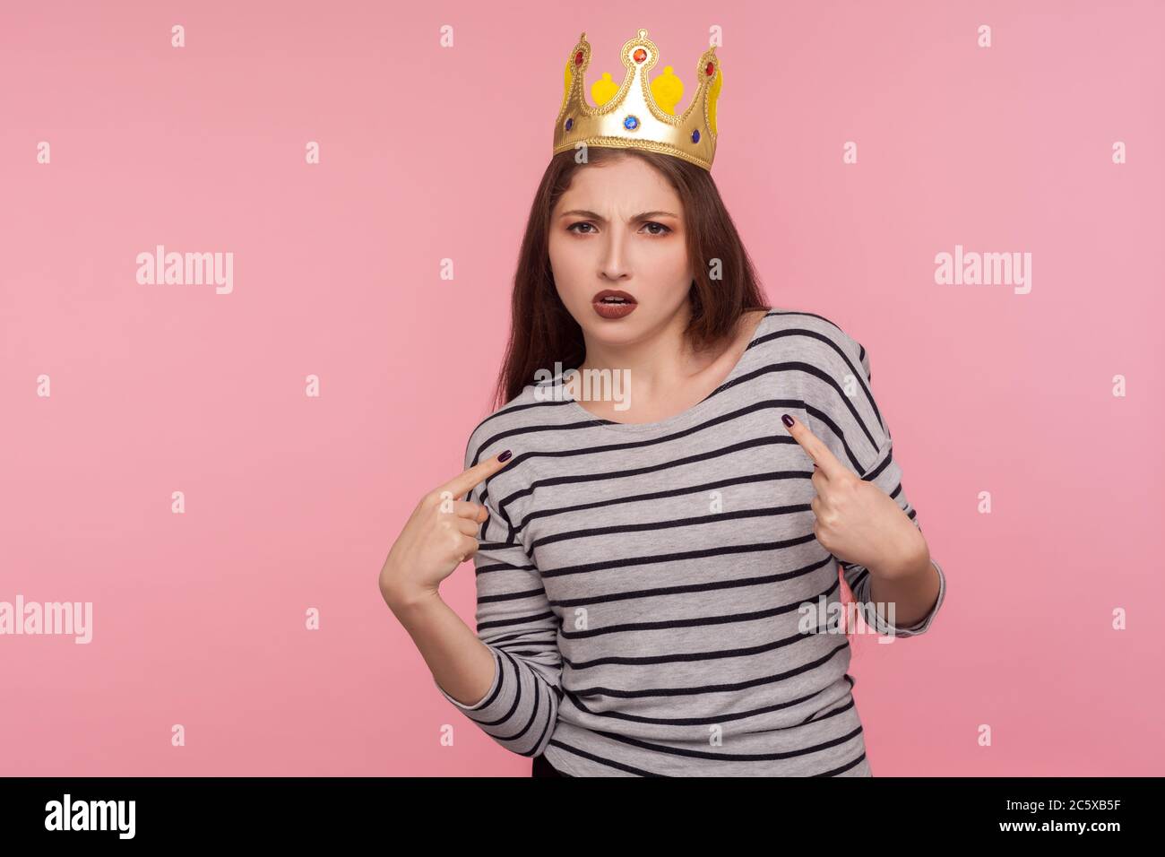 I'm boss! Portrait of selfish egoistic woman with golden crown on head pointing herself and looking with arrogance, declaring her authority, leadershi Stock Photo