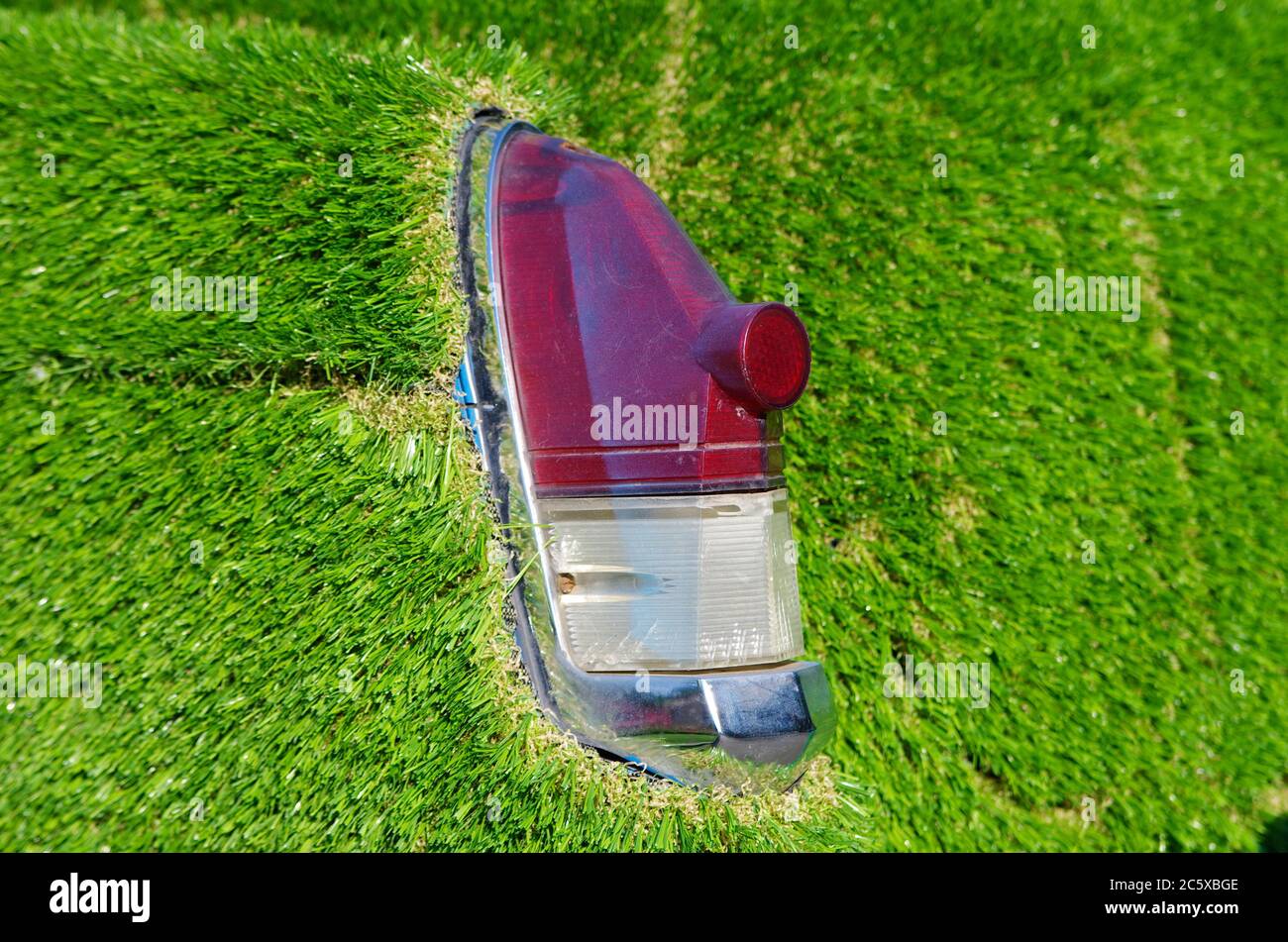 Old car rear lights with green artificial grass around. Scratches and dust on plastic cover.  Zero emissions vehicle concept Stock Photo